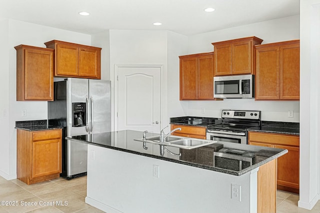 kitchen featuring a sink, appliances with stainless steel finishes, an island with sink, brown cabinets, and light tile patterned flooring