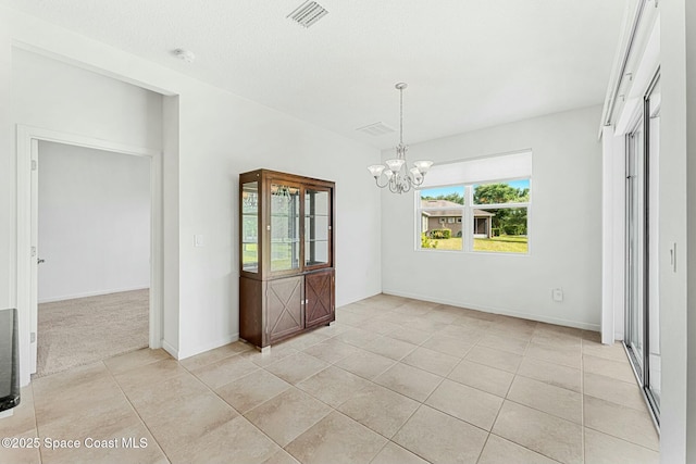 unfurnished dining area featuring an inviting chandelier, baseboards, visible vents, and light tile patterned floors