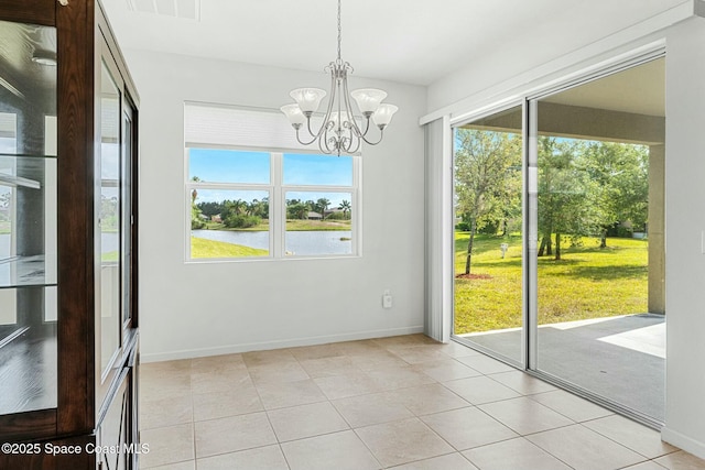 unfurnished dining area featuring a wealth of natural light, baseboards, a water view, and an inviting chandelier
