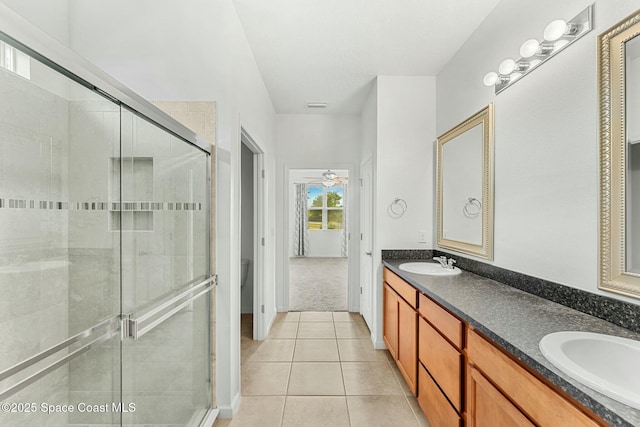 bathroom featuring a stall shower, double vanity, a sink, and tile patterned floors