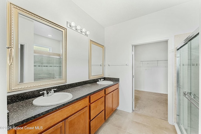 bathroom featuring a shower stall, a spacious closet, tile patterned flooring, a sink, and double vanity
