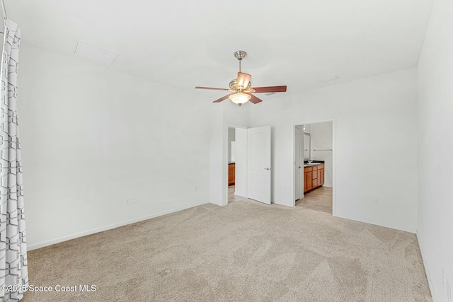 unfurnished bedroom featuring light carpet, ensuite bathroom, and baseboards