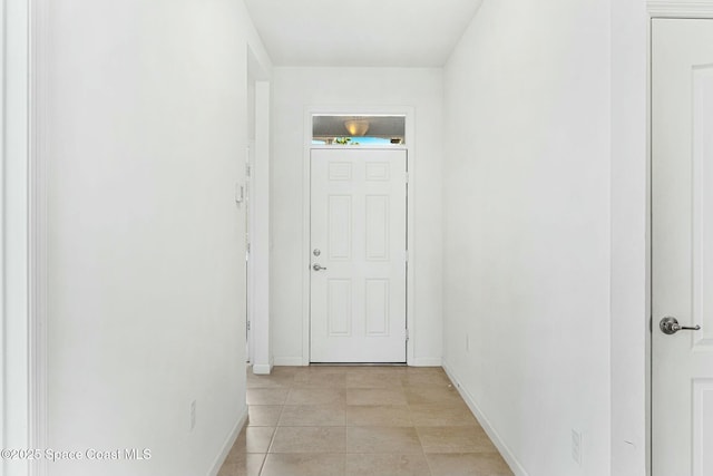 corridor with baseboards and light tile patterned flooring
