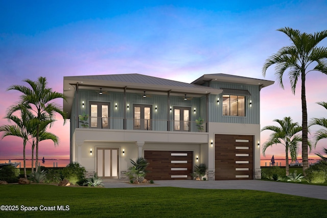 view of front facade featuring an attached garage, french doors, a balcony, and a front lawn
