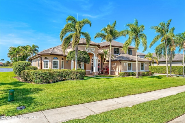 mediterranean / spanish-style house with a tiled roof, stucco siding, and a front lawn