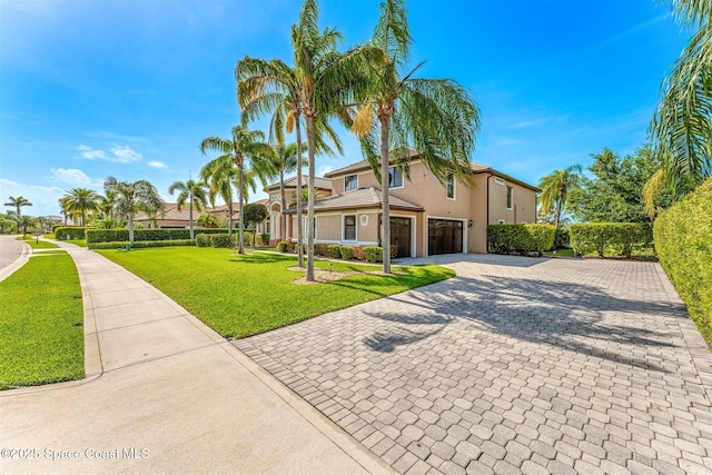 view of front of home featuring a front lawn, an attached garage, decorative driveway, and stucco siding
