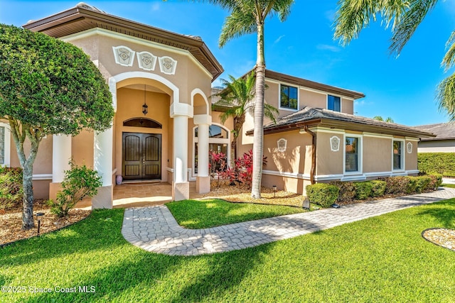 mediterranean / spanish home with a tile roof, a front lawn, and stucco siding