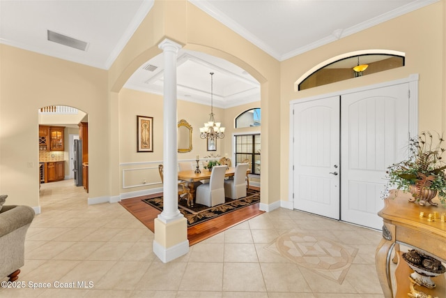 foyer featuring arched walkways, light tile patterned floors, visible vents, and crown molding