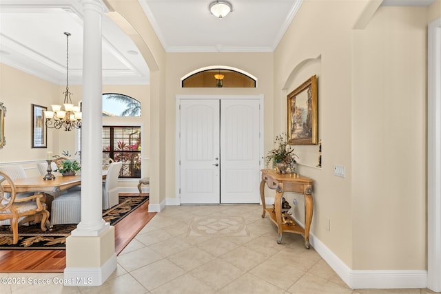 entrance foyer with baseboards, arched walkways, an inviting chandelier, ornamental molding, and light tile patterned flooring