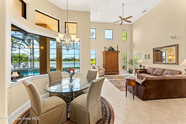 dining room with light tile patterned floors, a high ceiling, visible vents, a water view, and ceiling fan with notable chandelier