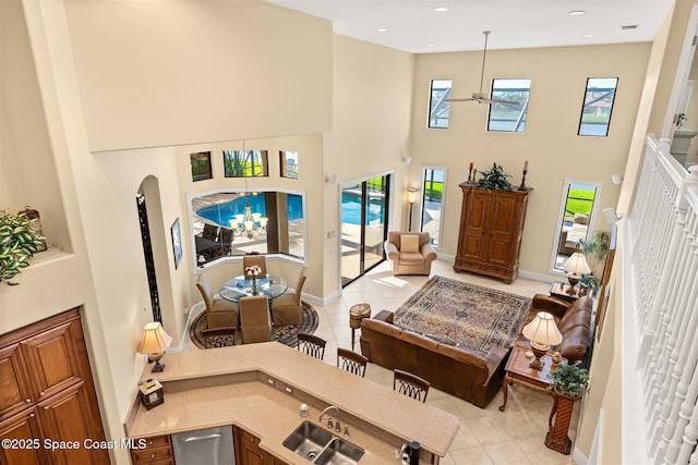 living room featuring light tile patterned floors, baseboards, plenty of natural light, and a high ceiling