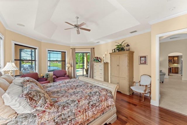 bedroom with access to outside, visible vents, a raised ceiling, arched walkways, and wood finished floors
