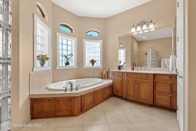 bathroom featuring tile patterned flooring, vanity, a garden tub, and a tile shower