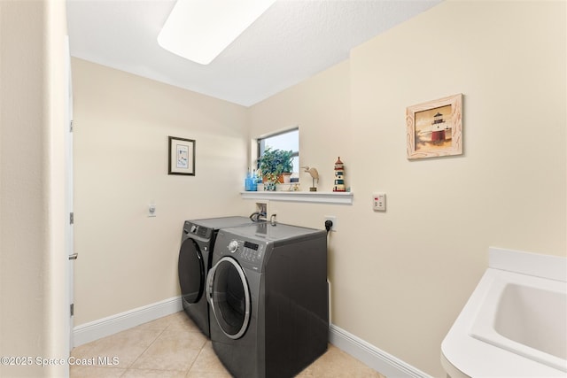 laundry room with light tile patterned floors, baseboards, washer and dryer, a sink, and laundry area