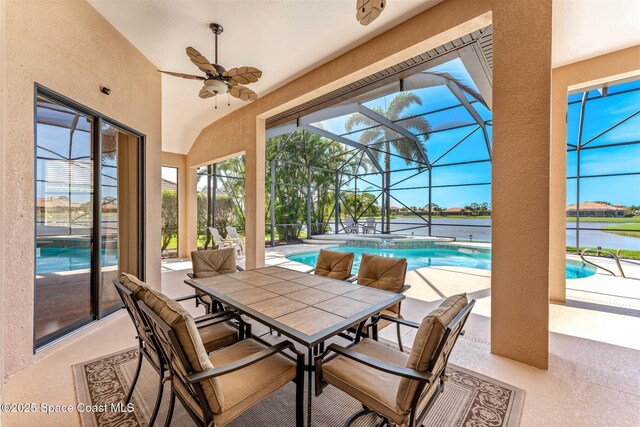 exterior space featuring a water view, a pool with connected hot tub, a ceiling fan, outdoor dining space, and glass enclosure
