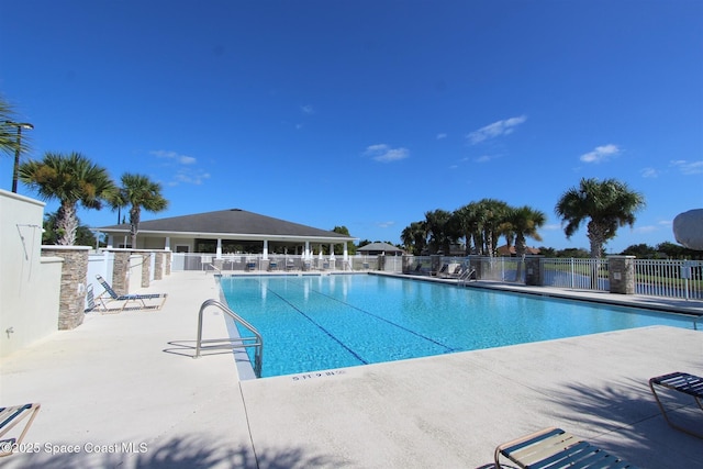 community pool with a patio area and fence