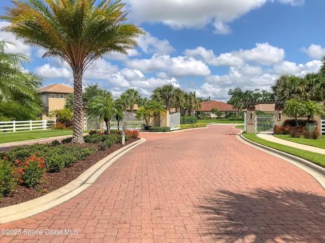 view of property's community featuring fence, a gate, and driveway