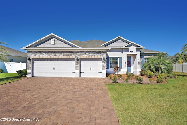 4710 Hebron Dr, Merritt Island, FL 32953 - view of front facade featuring stone siding, a garage, fence, a front lawn, and decorative driveway
