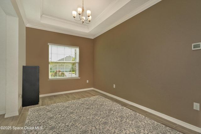 4710 Hebron Dr, Merritt Island, FL 32953 - spare room featuring a chandelier, a raised ceiling, ornamental molding, and wood finish floors