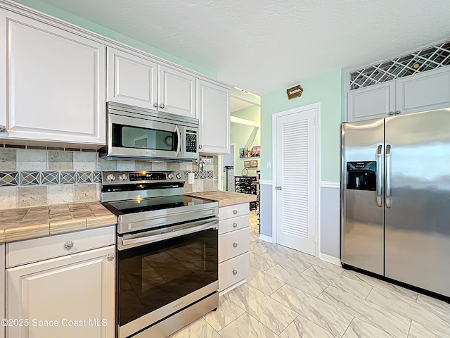 125 Terry St, Indian Harbour Beach, FL 32937 - kitchen with stainless steel appliances, marble finish floor, and white cabinetry