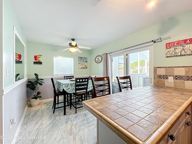 125 Terry St, Indian Harbour Beach, FL 32937 - dining area with marble finish floor, baseboards, a ceiling fan, and a textured ceiling