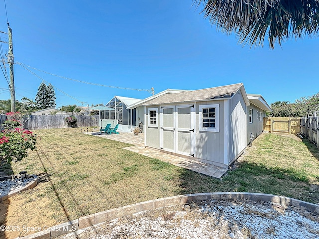 125 Terry St, Indian Harbour Beach, FL 32937 - rear view of house featuring a fenced backyard, a storage shed, an outbuilding, a lawn, and a sunroom