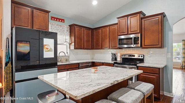 1546 Litchfield Dr, Melbourne, FL 32904 - kitchen featuring a sink, appliances with stainless steel finishes, a kitchen bar, vaulted ceiling, and dark wood-type flooring
