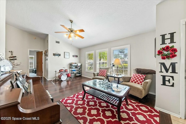 living area with ceiling fan, a textured ceiling, vaulted ceiling, visible vents, and baseboards