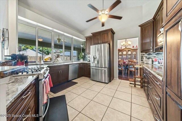kitchen with tasteful backsplash, a sink, a ceiling fan, vaulted ceiling, and stainless steel appliances