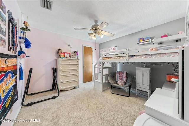bedroom with visible vents, a ceiling fan, carpet flooring, and a textured ceiling