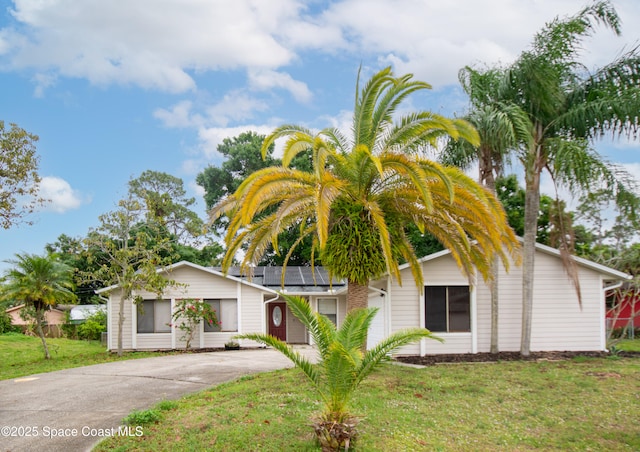 881 Brookson Ave NW, Palm Bay, FL 32907 - view of front of house with roof mounted solar panels, driveway, and a front yard