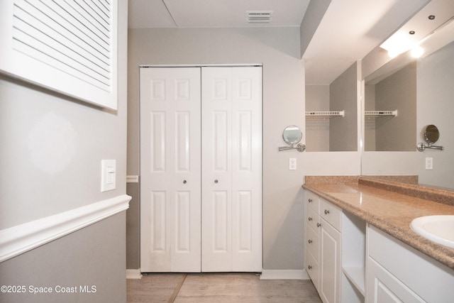 881 Brookson Ave NW, Palm Bay, FL 32907 - bathroom with wood finished floors, visible vents, vanity, a closet, and baseboards