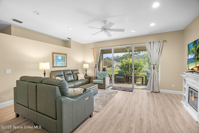 living area featuring light wood-type flooring, ceiling fan, and baseboards