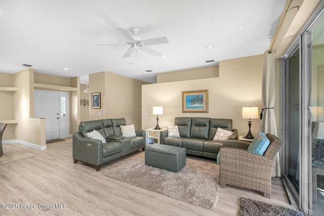 living area with visible vents, light wood-style flooring, a ceiling fan, and baseboards