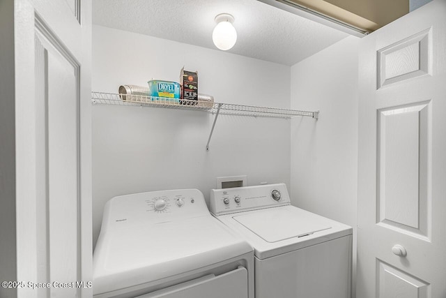 clothes washing area featuring separate washer and dryer, laundry area, and a textured ceiling