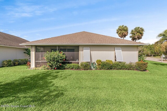 back of property with a sunroom and a lawn