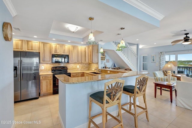 2470 Harbour Cove Dr, Hutchinson Island, FL 34949 - kitchen with light tile patterned floors, a raised ceiling, black appliances, light stone countertops, and backsplash