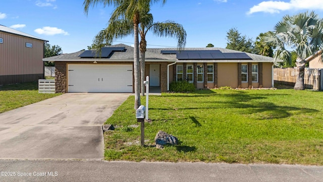 ranch-style home with roof mounted solar panels, a garage, a front yard, fence, and concrete driveway