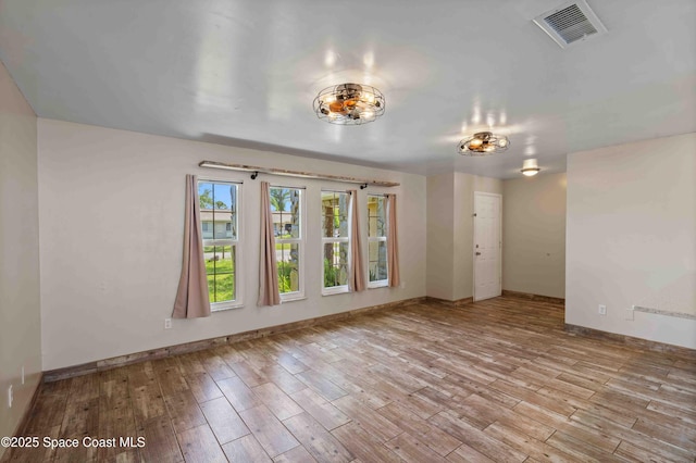 unfurnished room with wood finished floors, baseboards, and visible vents