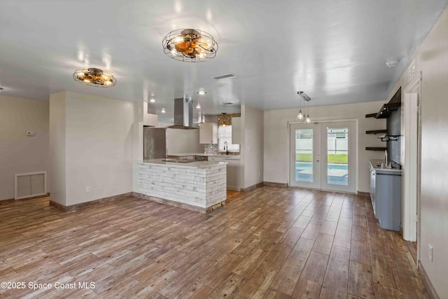 interior space featuring visible vents, light countertops, wood finished floors, and a peninsula