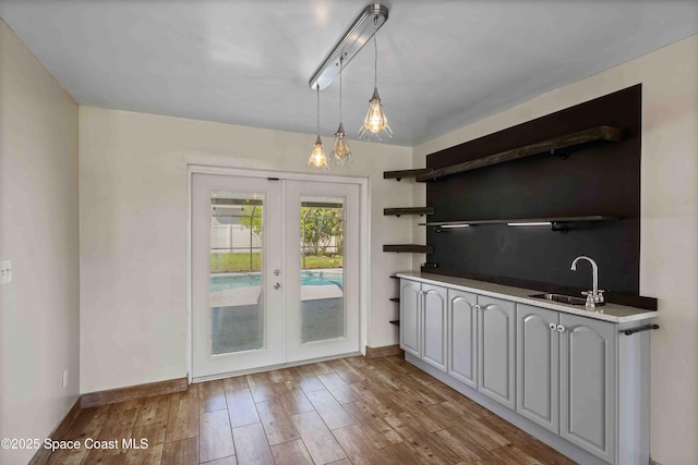 interior space with french doors, baseboards, a sink, and wood finished floors