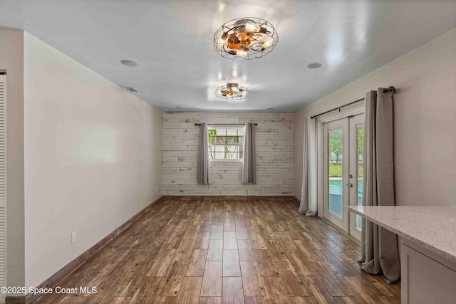 unfurnished dining area featuring french doors, dark wood-style floors, visible vents, and a wealth of natural light