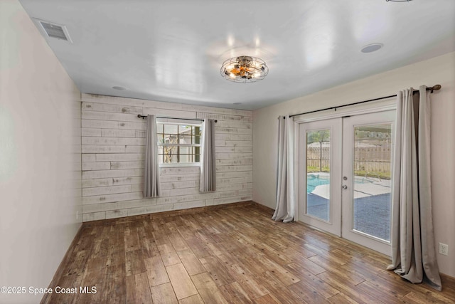 spare room featuring french doors, baseboards, wood-type flooring, and visible vents