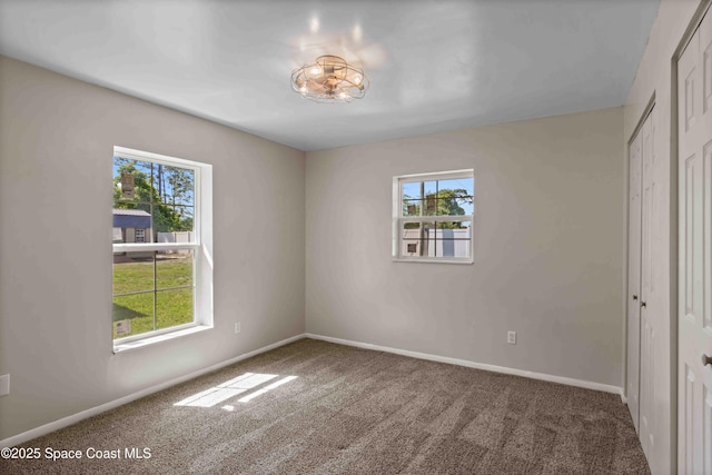 unfurnished bedroom featuring carpet flooring, multiple windows, and baseboards