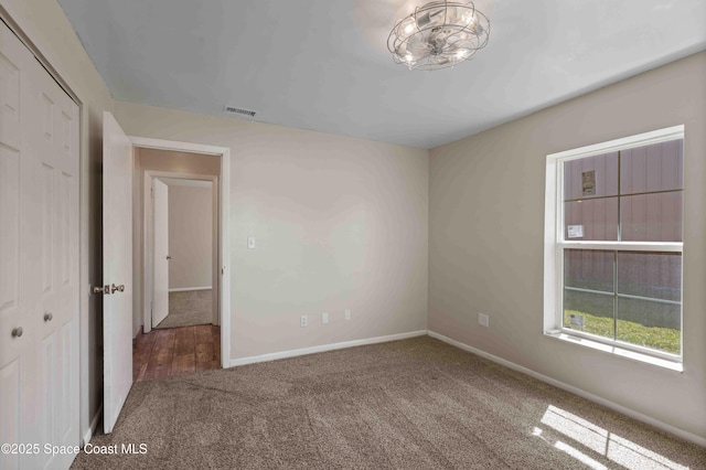 unfurnished room with baseboards, visible vents, and carpet floors
