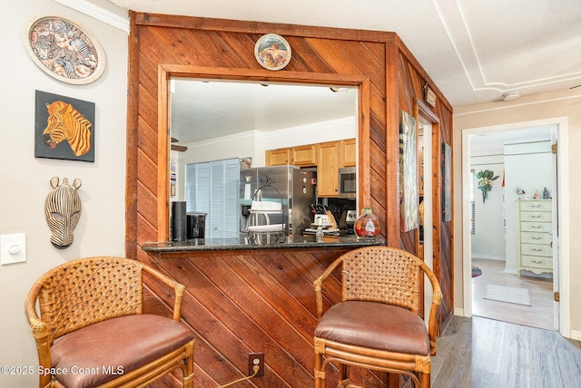 kitchen featuring crown molding, appliances with stainless steel finishes, wood finished floors, and a breakfast bar