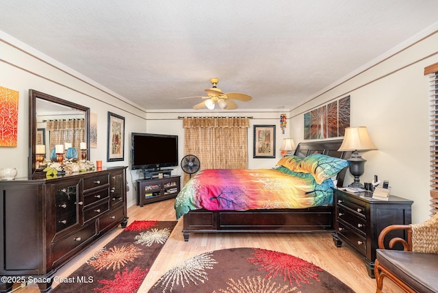 bedroom with a ceiling fan, ornamental molding, and wood finished floors