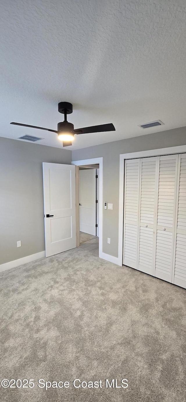 unfurnished bedroom featuring carpet flooring, visible vents, a textured ceiling, and baseboards