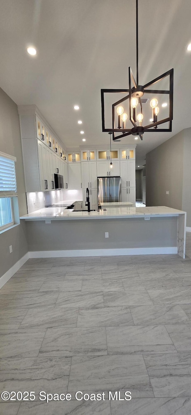 kitchen featuring white cabinets, light countertops, baseboards, and stainless steel fridge