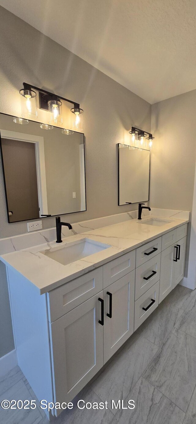 full bathroom with double vanity, marble finish floor, and a sink